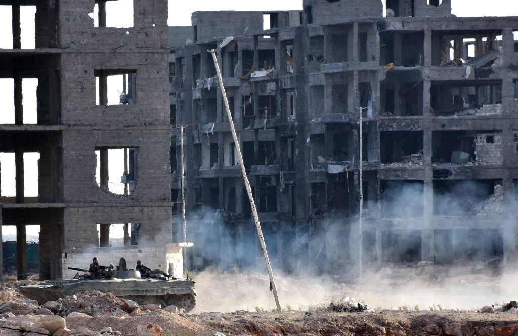 Syrian pro-government forces drive past heavily damaged buildings in Aleppo's 1070 district on November 8, 2016, after troops seized it from rebel fighters.  AFP / GEORGES OURFALIAN
