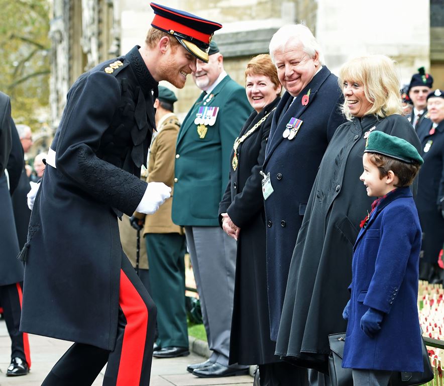 Britain's Prince Harry (L) reacts after shaking hands with a young boy during his visit to the Field of Remembrance at Westminster Abbey in central London on November 10, 2016. AFP / POOL / Eddie Mulholland
