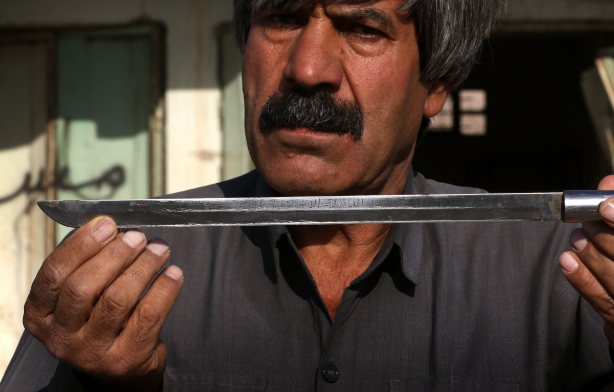 An Iraqi Kurdish man shows a knife engraved with a slogan in Arabic, 
