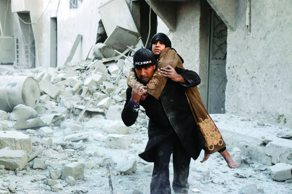 A Syrian rescuer carries a woman who was rescued from the rubble of a building following reported airstrikes on Aleppo's rebel-held district of Al Hamra, yesterday.