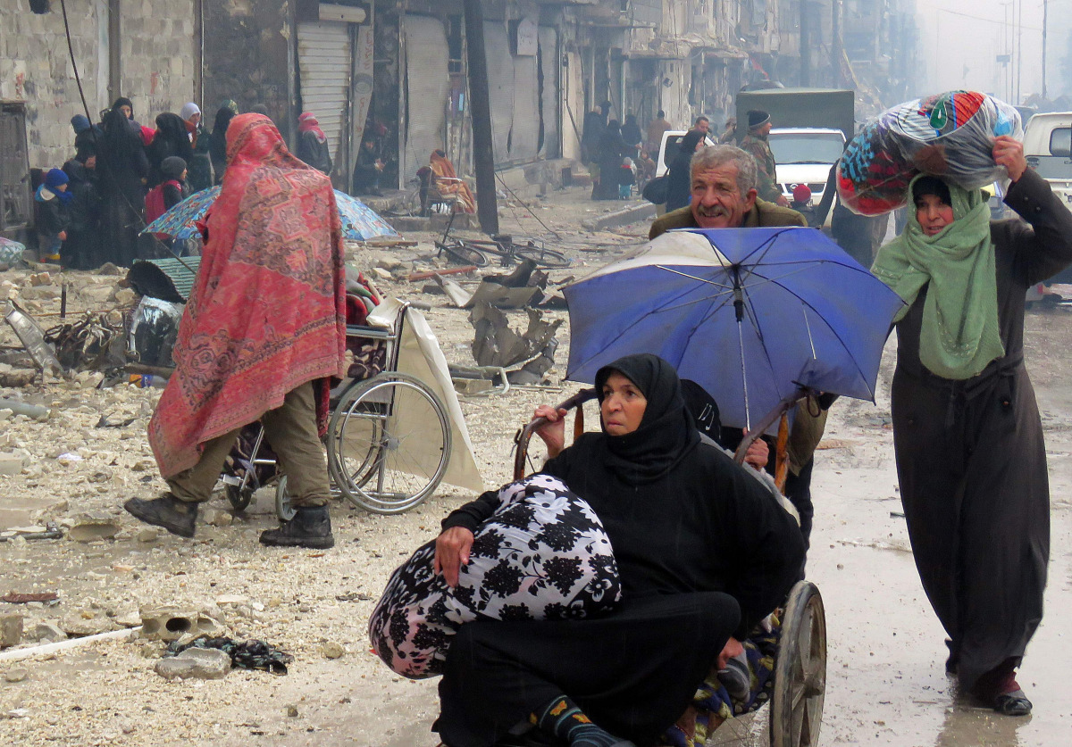 Syrian residents, fleeing violence in the restive Bustan al-Qasr neighbourhood, arrive in Aleppo's Fardos neighbourhood on December 13, 2016, after regime troops retook the area from rebel fighters. Syrian rebels withdrew from six more neighbourhoods in t