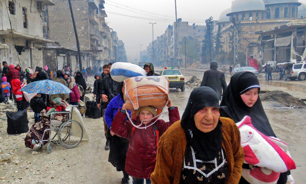 Syrian residents, fleeing violence in the restive Bustan al-Qasr neighbourhood, arrive in Aleppo's Fardos neighbourhood on December 13, 2016, after regime troops retook the area from rebel fighters.  AFP / STRINGER
