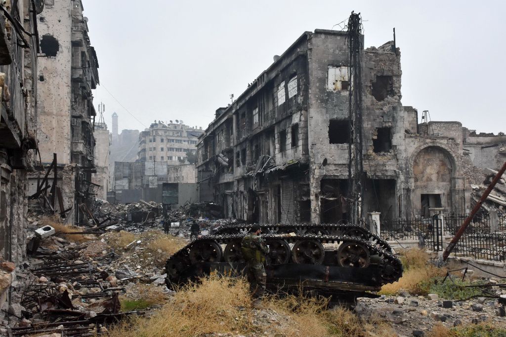 A member of the Syrian pro-government forces stands next to a tank in the old city of Aleppo on December 13, 2016, after they recaptured the area. After weeks of heavy fighting, regime forces were poised to take full control of Aleppo, dealing the biggest