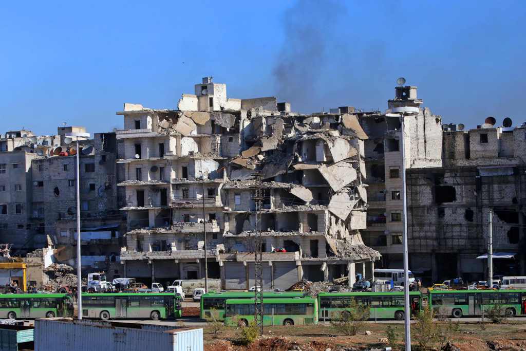 Buses which will be used to evacuate rebel fighters and their families from rebel-held areas of Aleppo are seen waiting on December 15, 2016.  AFP / Youssef KARWASHAN

