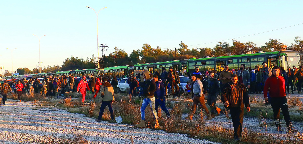Evacuees from rebel-held east Aleppo, disembark from buses upon their arrival at the town of Al Rashideen