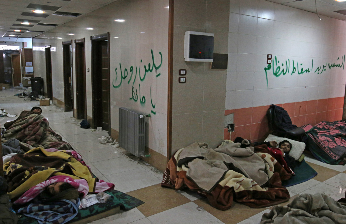Injured and sick people wait inside a hospital to be evacuated from a rebel-held sector of eastern Aleppo, Syria December 17, 2016. The arabic on the wall reads: 'The people want to bring down the regime' (R) and 'Curse your soul, oh Hafez' (L). REUTERS/A