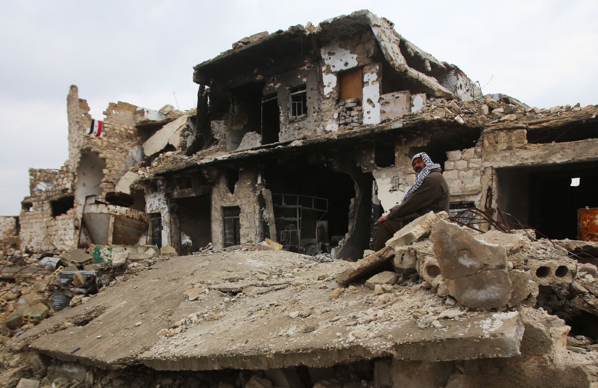 A Syrian man sits on the rubble of his house in Aleppo's Al-Arkoub neighbourhood on December 17, 2016, after pro-government forces retook the area from rebel fighters. / AFP / Youssef KARWASHAN