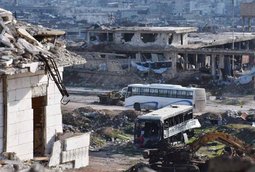 A bus drives through the government-controlled crossing of Ramoussa, on the southern outskirts of Aleppo, on December 18, 2016, during an evacuation operation of rebel fighters and civilians from rebel-held areas. George Ourfalian/AFP.