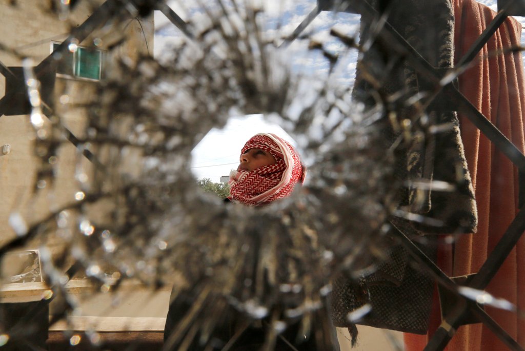 A boy is pictured through a bullet hole in a window inside a building that was the site of clashes between Jordanian police and Islamist militant gunmen in the village of Garifla, in Karak, Jordan, December 21, 2016. REUTERS/Muhammad Hamed
