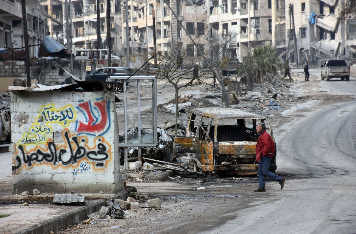 A Syrian man walks past the wreckage of cars in the former rebel-held Ansari district in the northern Syrian city of Aleppo on December 23, 2016 after Syrian government forces retook control of the whole embattled city. Syrian troops cemented their hold o