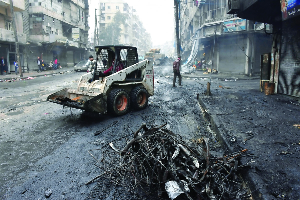 A tractor removes rubble as the Syrian government starts to clean up areas formerly held by opposition forces in the northern city of Aleppo, yesterday.