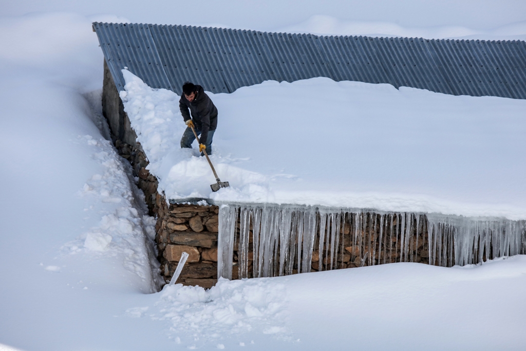 A man shovels snow off a roof due to inclement weather conditions in Van, Turkey on December 27, 2016. Ali ?hsan Öztürk - AA