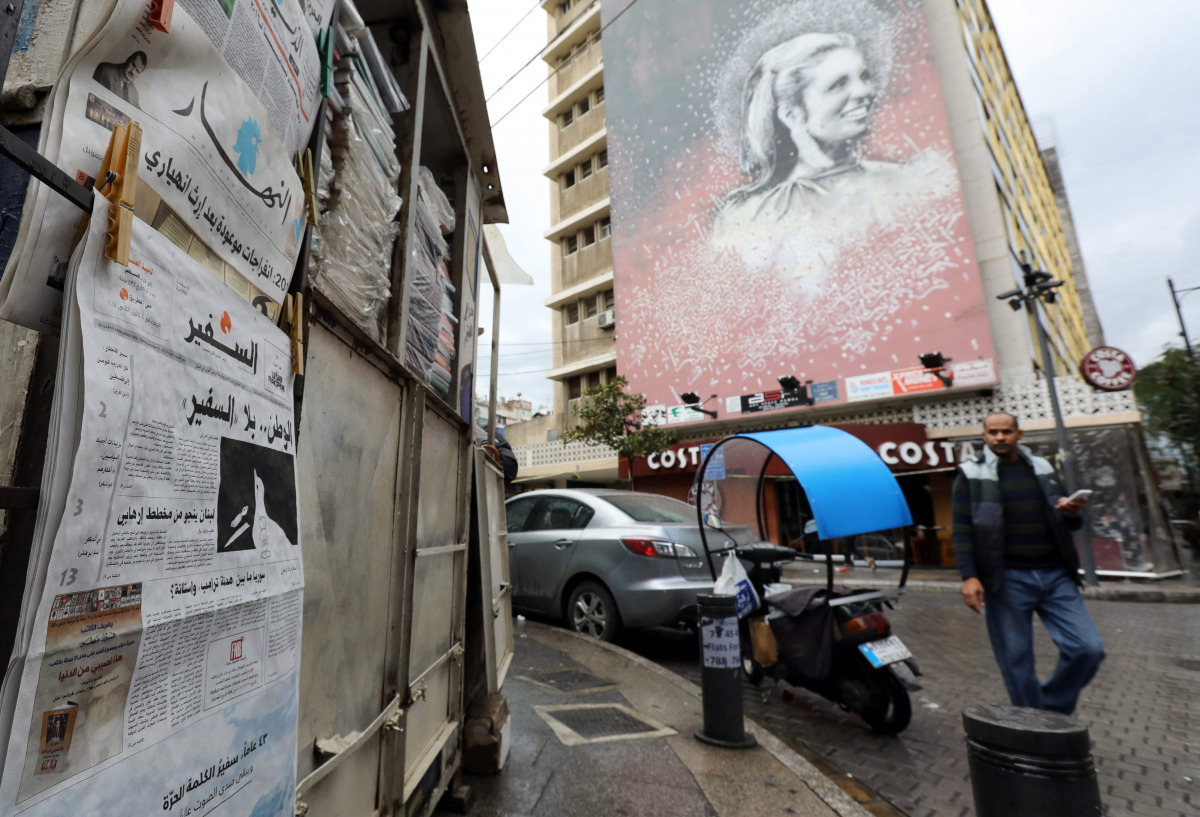 A man walks past a newspaper stand, displaying the As-Safir newspaper, in Beirut's Hamra neighborhood on December 31, 2016. The Arabic political daily newspaper based in Beirut, As-Safir meaning 'The Ambassador', was founded in March of 1974 and had been 