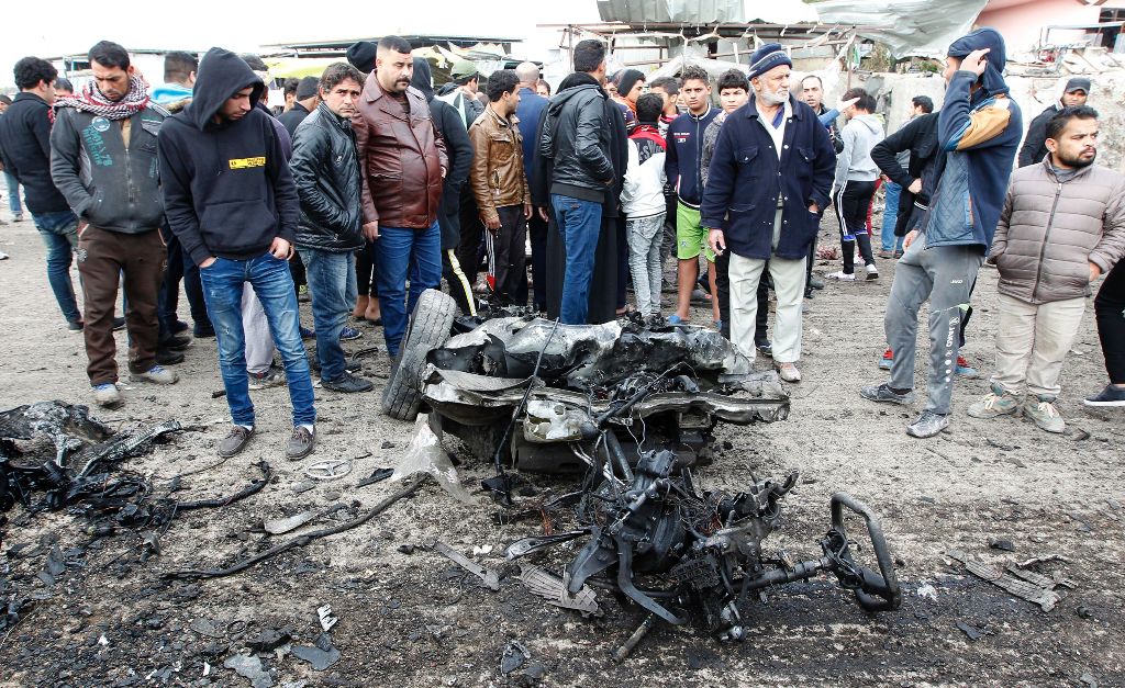 Iraqis inspect a charred vehicle on the site of a bomb attack in Sadr City, a majority Shiite neighbourhood in the northeast of the capital Baghdad, on January 2, 2017. A suicide car bomb attack in a densely-populated neighbourhood of Baghdad killed at le