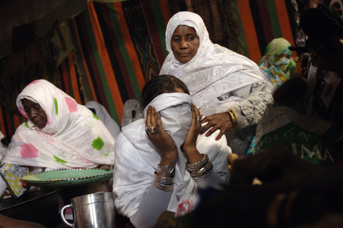 Algerian women help a bride cover her face during a group wedding ceremony, organised by a charity for economically disadvantaged people and orphans, in the Sahara desert village of In-Salah, south Algeria, on December 21, 2016.
