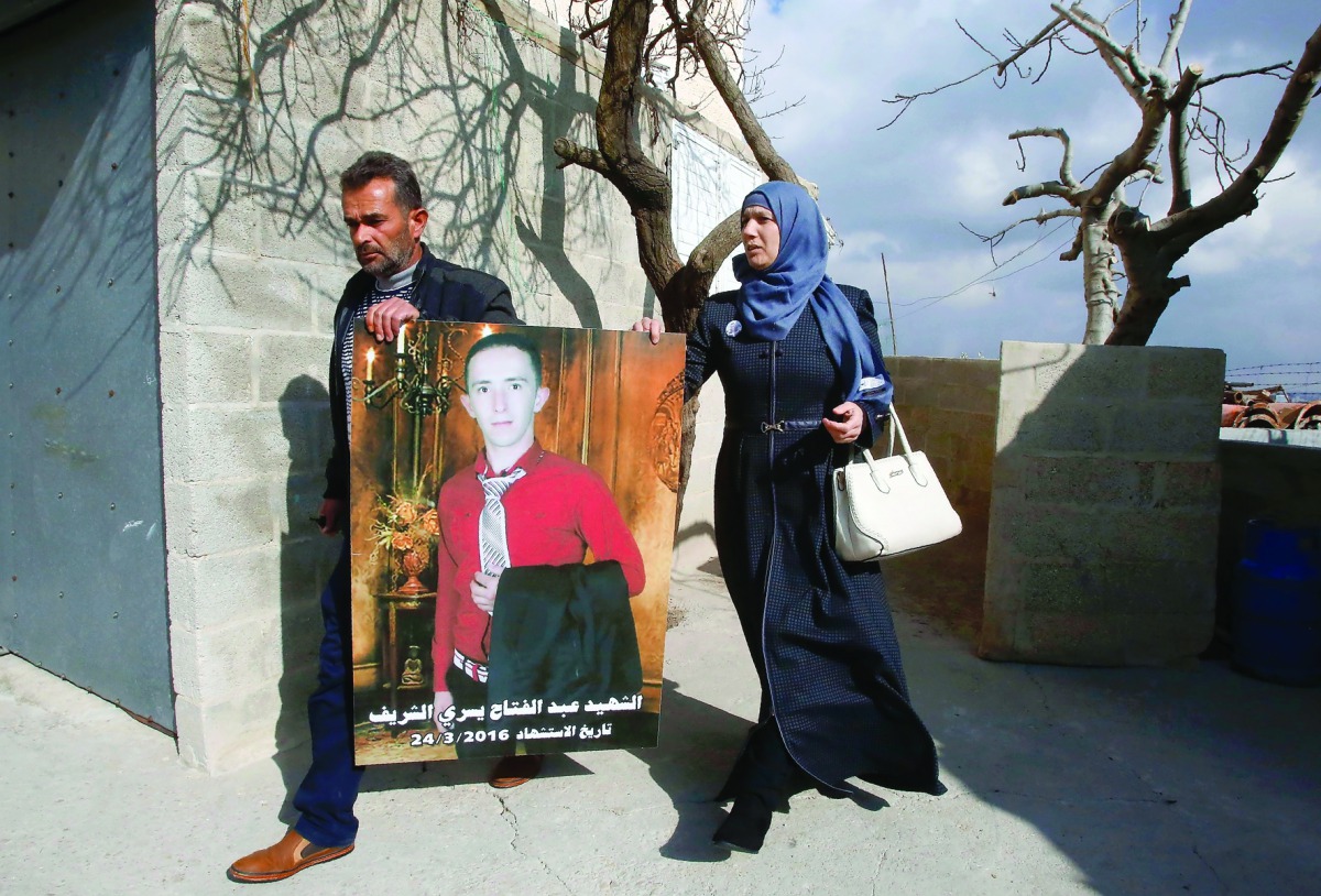 Rajaa and Yousri, parents of Abdul Fatah Al Sharif (portrait) head out into the streets in the West Bank town of Hebron.