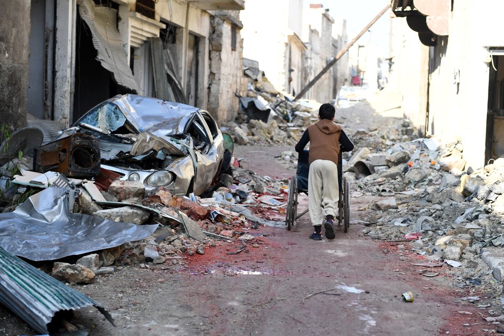 A boy pushes a wheelchair along a damaged street in the east Aleppo neighborhood of al-Mashatiyeh, Syria, in this handout picture provided by UNHCR on January 4, 2017. Bassam Diab
