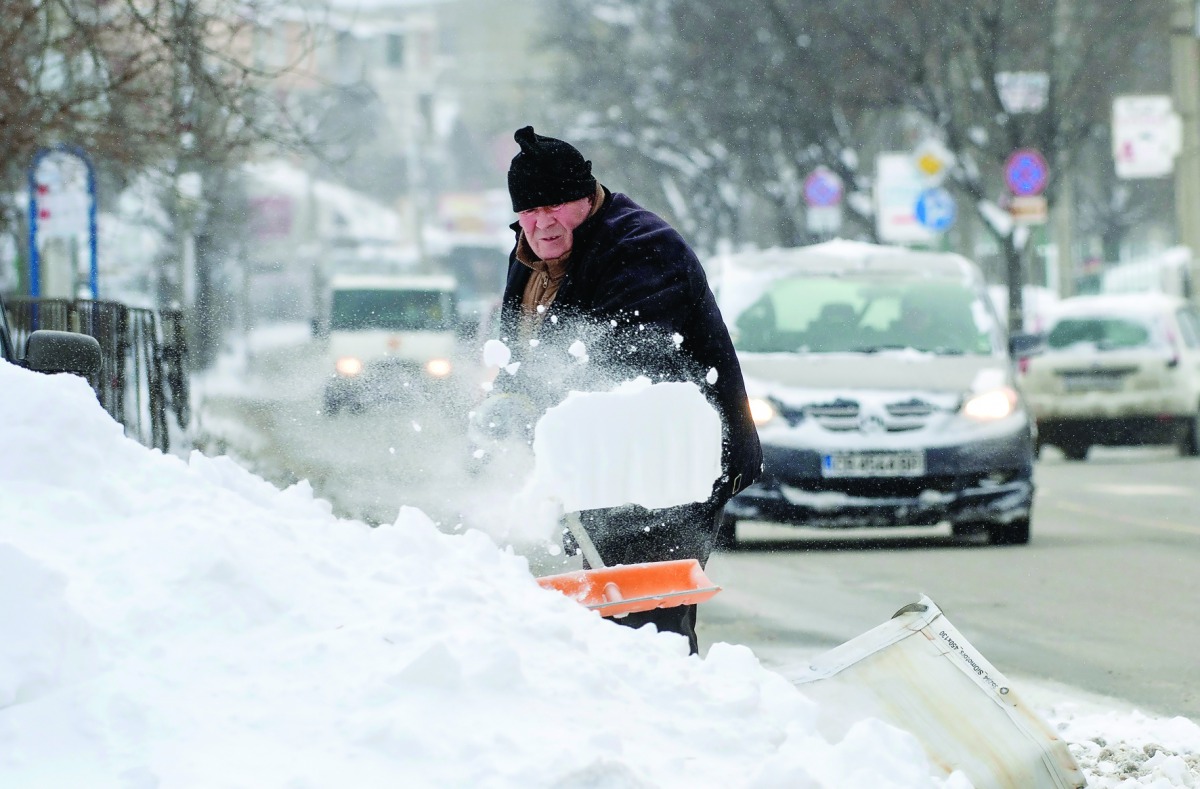 A man removes snow from a car in a suburb of Sofia in Bulgaria after heavy snowfall yesterday. Snowstorms and temperatures plunging to minus 19 degrees Celsius have brought road traffic to a standstill across the country, officials said.