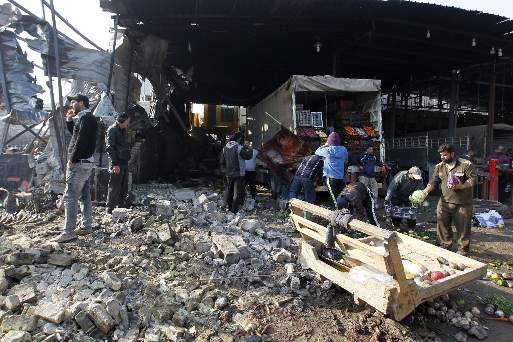 Iraqis salvage vegetables from the site of an attack at Baghdad's main vegetable market on January 8, 2017. A suicide bomber blew up a car at the entrance of the market, killing at least 11 people and wounding dozens, security officials and medics said. /