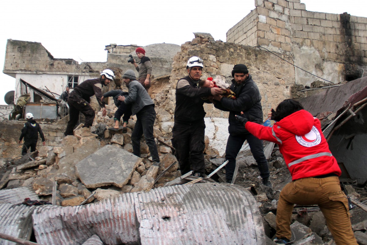 Syrian Civil Defence volunteers, also knowns as the White Helmets, rescue children from a damaged building following a reported airstrike that targeted the Idlib bus station on January 18, 2017. AFP / Omar Haj Kadour