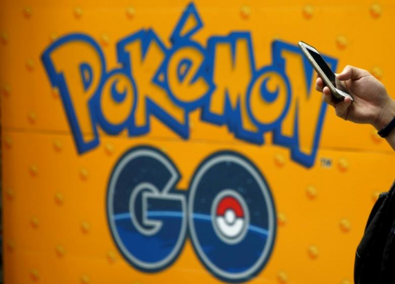A man uses a mobile phone in front of an advertisement board bearing the image of Pokemon Go at an electronic shop in Tokyo, Japan. Reuters/Kim Kyung-Hoon/File Photo

