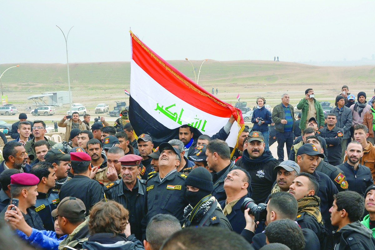 Iraqi people raise the national flag in the same place where Islamic State militants raised their flag two years ago in east Mosul, Iraq, yesterday.