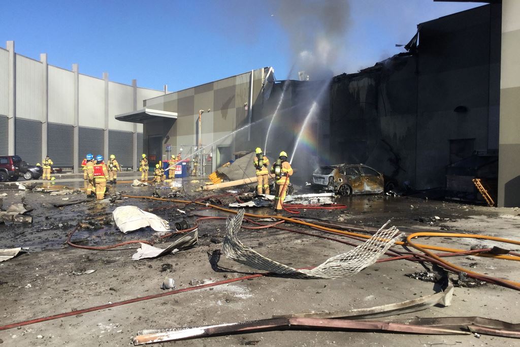 This handout photo released by the Metropolitan Fire Brigade (MFB) media shows firemen putting out a blaze from a light aircraft which exploded as it smashed into a shopping centre near Melbourne on February 21, 2017. AFP / METROPOLITAN FIRE BRIGADE MEDIA
