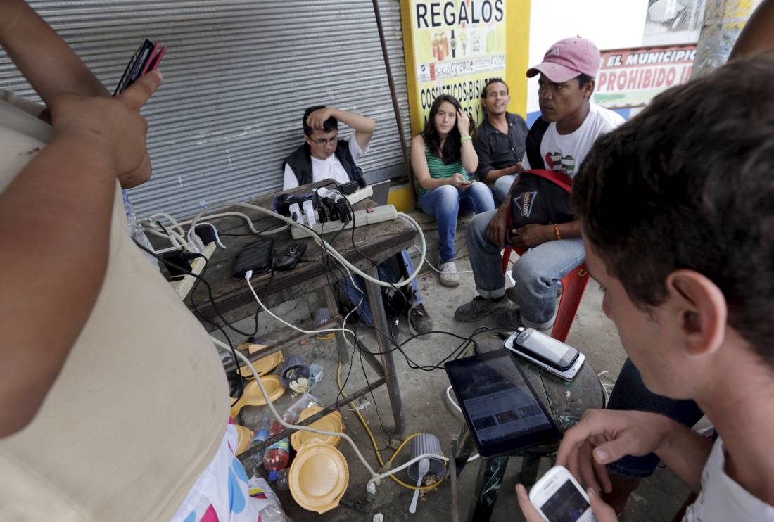 Residents use the internet via free wifi and charge their mobile phone batteries along a sidewalk in Pedernales, after an earthquake struck off Ecuador's Pacific coast, April 23, 2016. REUTERS/Henry Romero