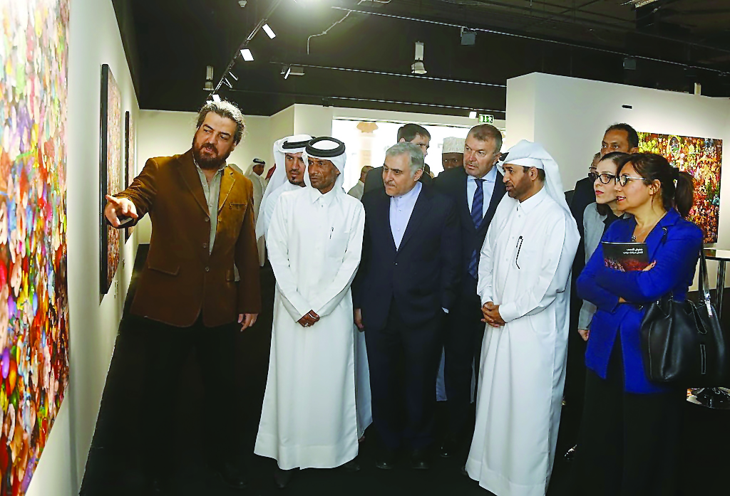 Iranian artist Siamak Azmi (left) explains one of his paintings to Katara General Manager Dr Khalid bin Ibrahim Al Sulaiti (third right) as other guests look on.