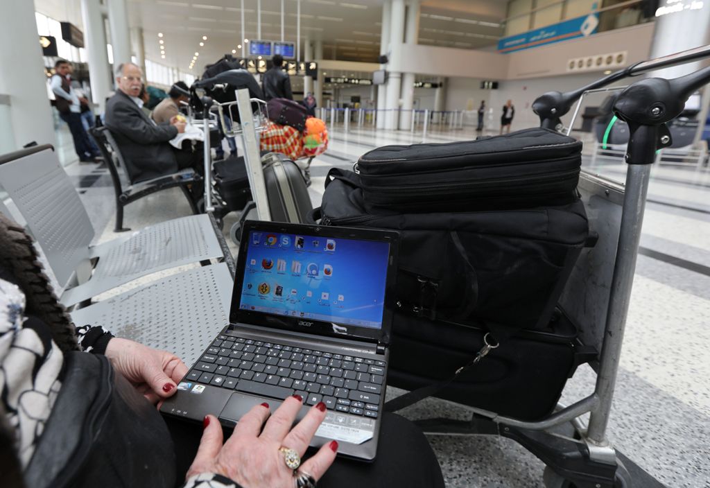 A Syrian woman travelling to the United States through Amman opens her laptop before checking in at Beirut international airport on March 22,2017.  AFP / ANWAR AMRO