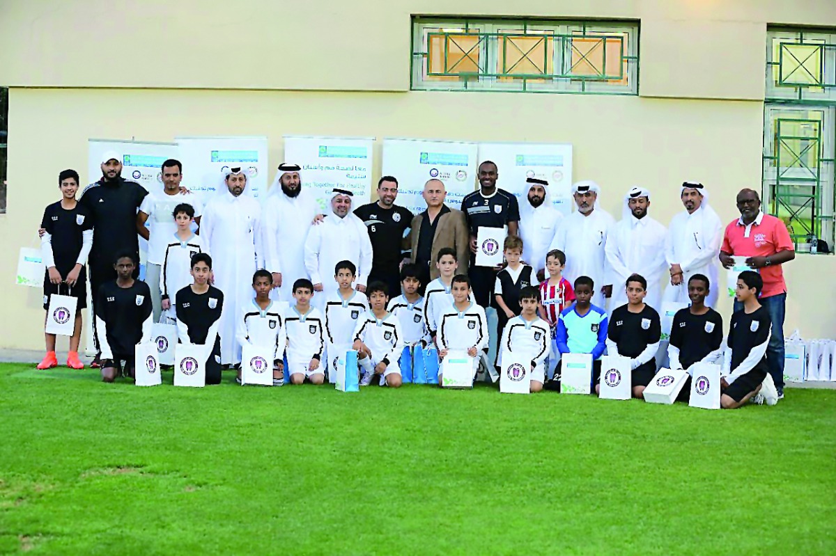 Dr Darwish poses for a group photo alongside famous football players – Abdulkarim Hassan, Al Sadd Sports Club player and Xavi Hernandez, Barcelona FC player – and other officials and students during an event held at the Al Sadd Sports Club to mark the Wor