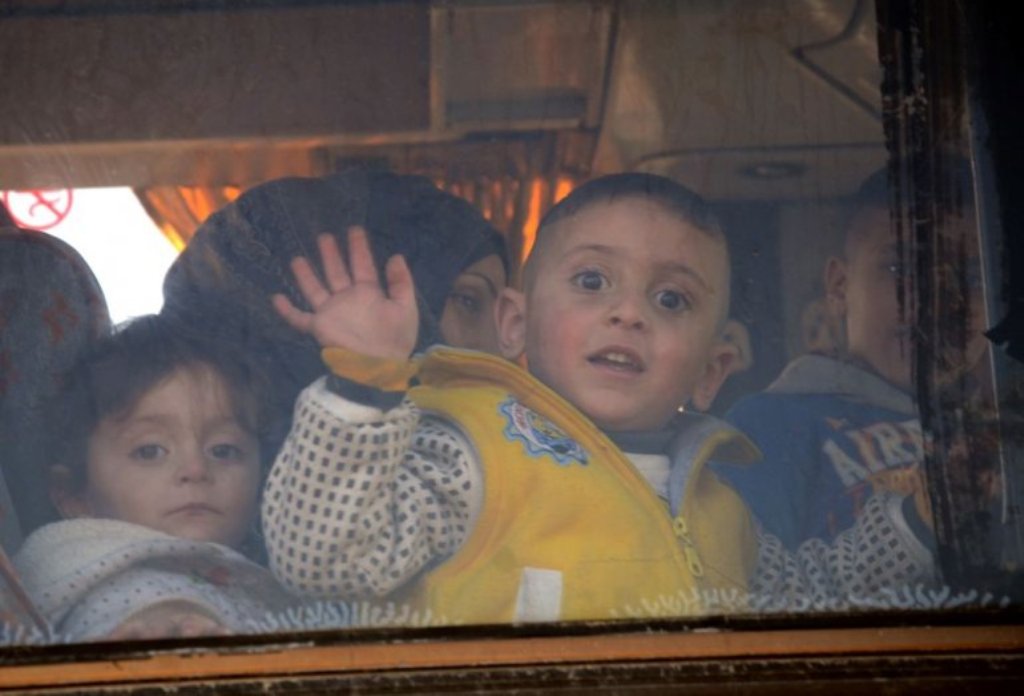 (File Photo) A child waves from the window of a bus as Syrians who were evacuated from Waer, the last opposition-held district of Homs, arrive in the northern Syrian town of al-Bab on March 19, 2017, under a controversial Russian-supervised deal to bring 