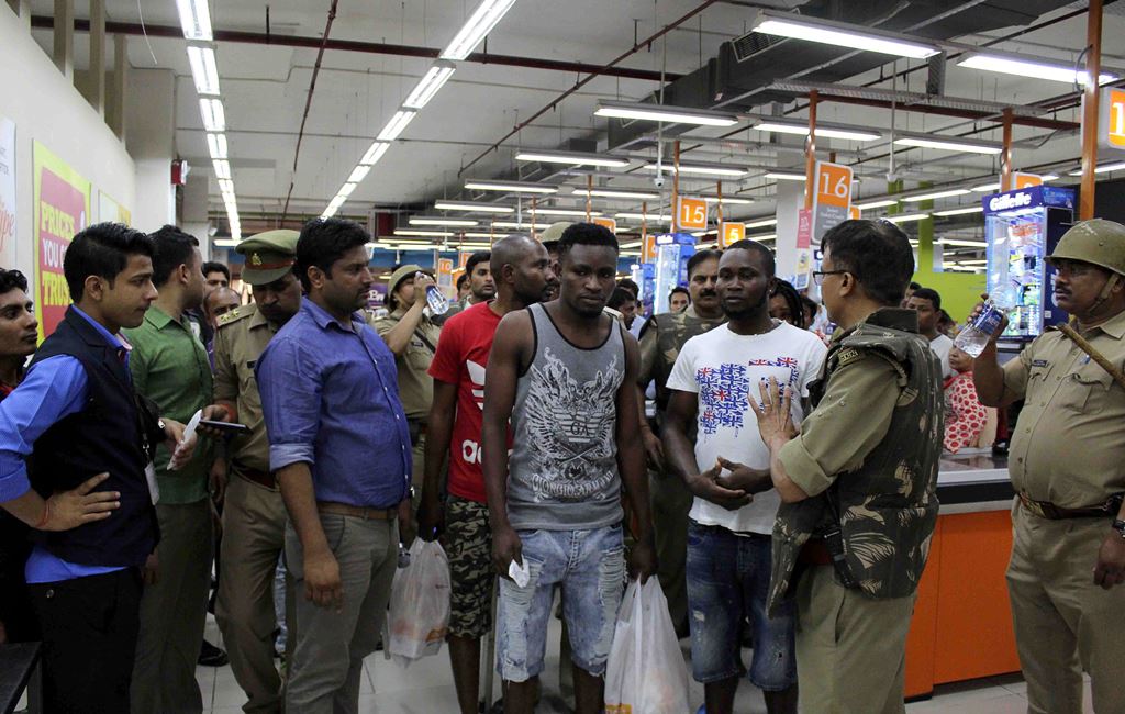 This photo taken on March 27, 2017 shows Indian police and onlookers surrounding African nationals at a shopping mall in Greater Noida. AFP