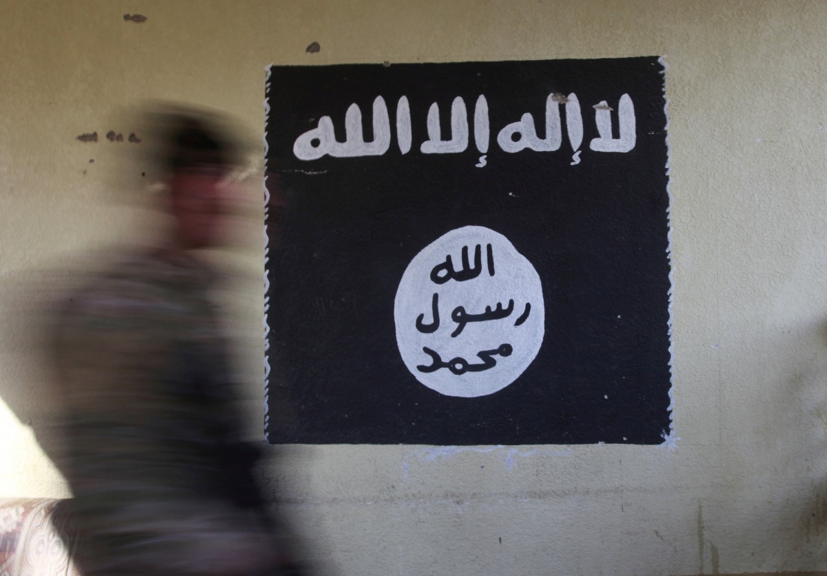 An Iraqi forces member walks past a wall painted with the black flag used by Islamic State militants at a hospital damaged by clashes in the Wahda district of eastern Mosul January 8, 2017 (REUTERS Alaa A)