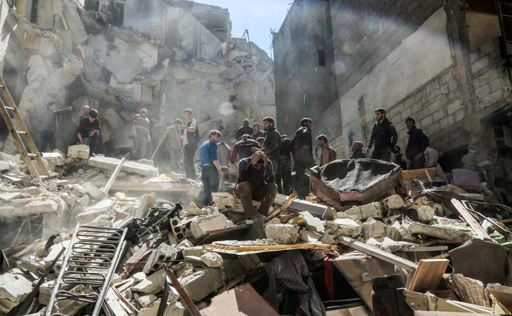 A Syrian mourns as members of the Syrian civil defence volunteers, also known as the White Helmets, and people search for survivors from the rubble following reported air-strikes on the rebel-held town of Saqba, in Eastern Ghouta, on April 4, 2017. / AFP 