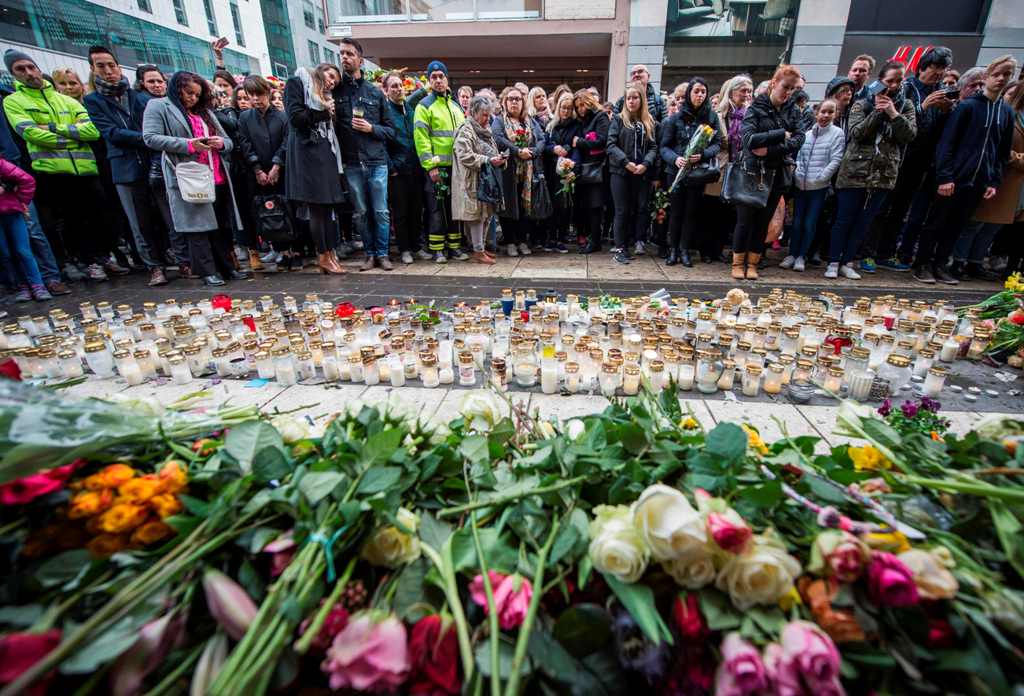 People react during a minute of silence to commemorate the victims of Friday's terror attack at a makeshift memorial near the site where a truck drove into Ahlens department store in Stockholm, Sweden, on April 10, 2017. / AFP / Jonathan NACKSTRAND