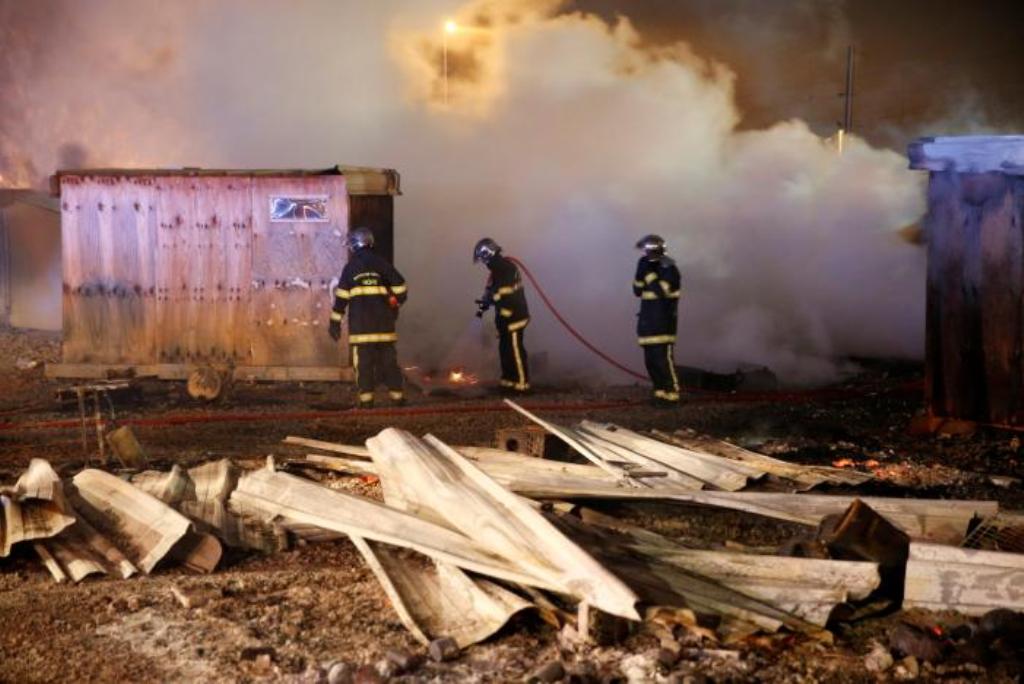 Firefighters extinguish shelters during a fire which destroyed many wood houses at a camp for migrants in Grande-Synthe, near Dunkirk, France, April 11, 2017. REUTERS/Pascal Rossignol.