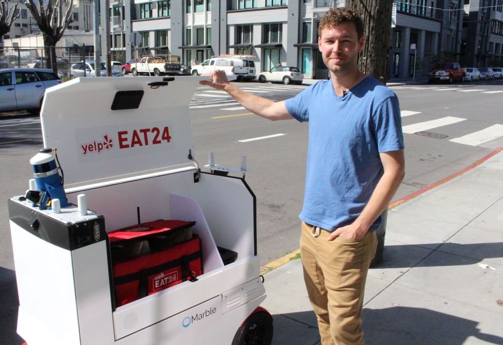 Marble co-founder and chief Matthew Delaney prepares a Happy ground-delivery robot to head off with a load outside the startup's headquarters in San Francisco, California on March 29, 2017.   AFP / Glenn CHAPMAN
