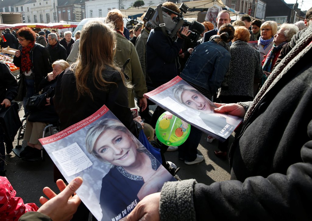 Supporters of French far right National Front political party leader Marine Le Pen distribute political leaflets as part of the 2017 French presidential election at a local market in Henin-Beaumont, France, April 7, 2017. Picture taken, April 7, 2017. Reu