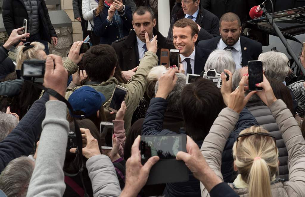 French presidential election candidate for the En Marche! movement, Emmanuel Macron (Rear C-R) meets with supporters outside his house after voting in Le Touquet, northern France, on April 23, 2017, during the first round of the presidential election. AFP