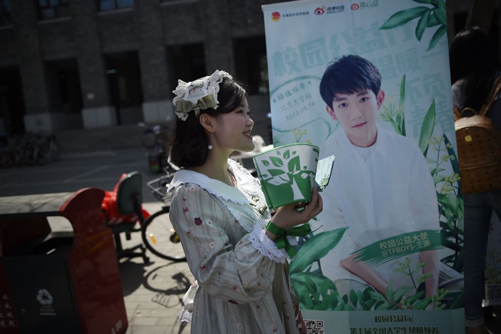 This picture taken on April 14, 2017 shows a woman handing out leaflets during an event for fans of China's boy band sensation TFBoys 