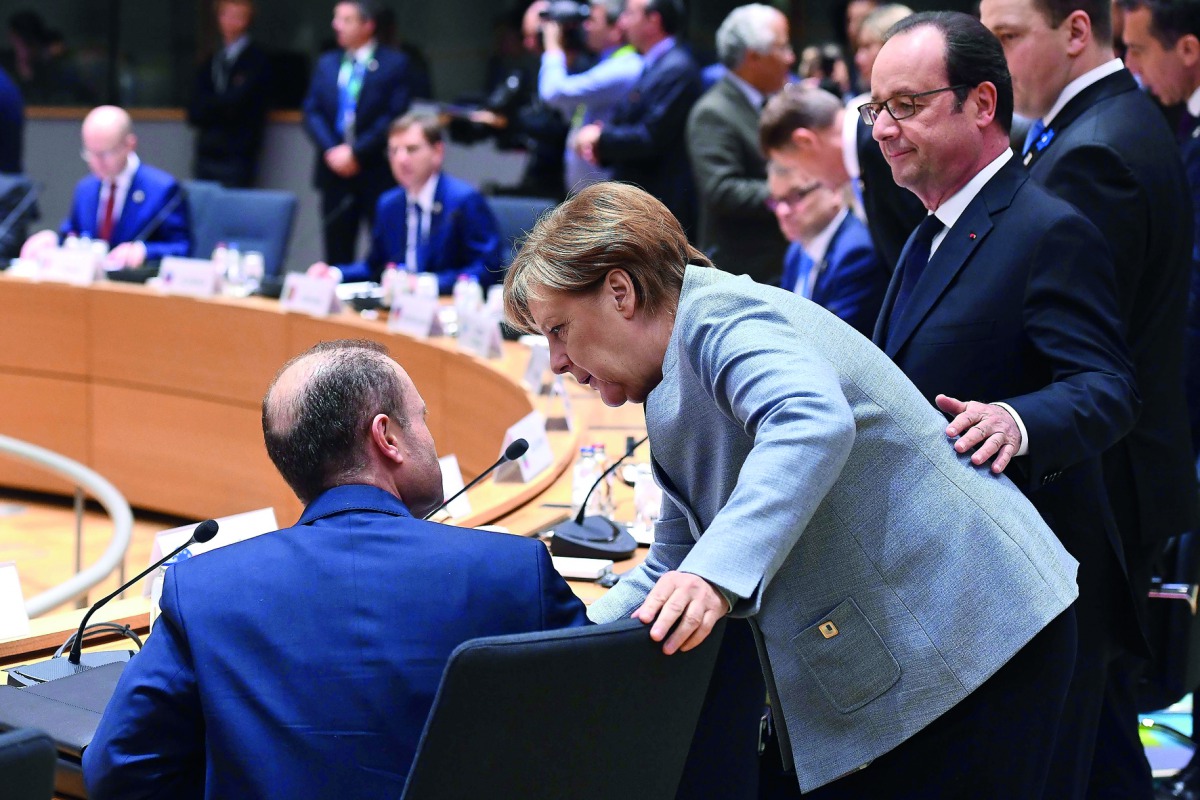 German Chancellor Angela Merkel (centre) speaks with Maltese Prime Minister Joseph Muscat (left) while French President Francois Hollande looks on during a special EU leaders' meeting at the main headquarters of European Council and the Council of the EU,