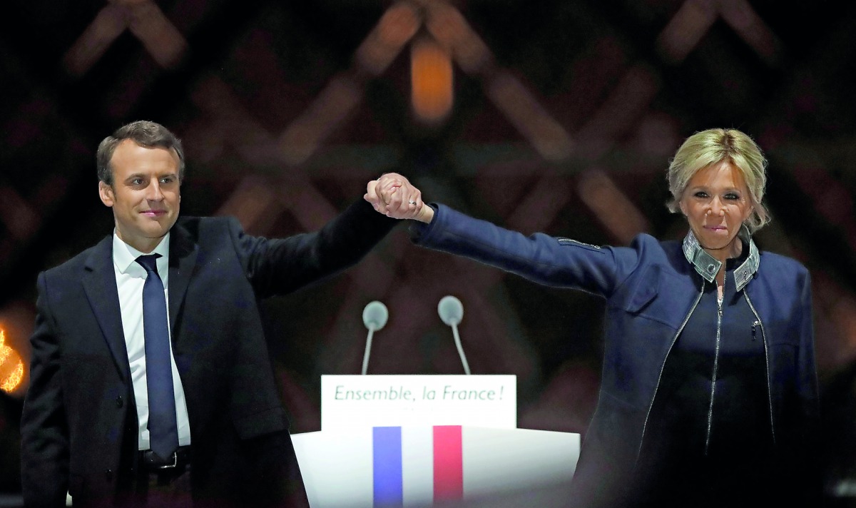 French President-elect Emmanuel Macron and his wife Brigitte Trogneux celebrate on the stage at his victory rally near the Louvre in Paris.