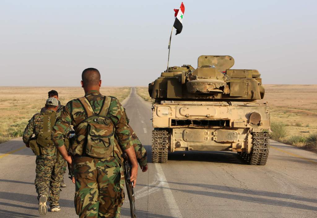 Syrian government forces secure a road for a military convoy in the desert area of Saba' Biyar, in southeastern Syria near the border with Iraq, on May 10, 2017, as fierce clashes are reported in the region. / AFP 