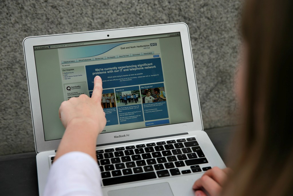 In this posed picture photograph, a woman points to the website of the NHS: East and North Hertfordshire notifying users of a problem in its network, in London on May 12, 2017. AFP / Daniel LEAL-OLIVAS

