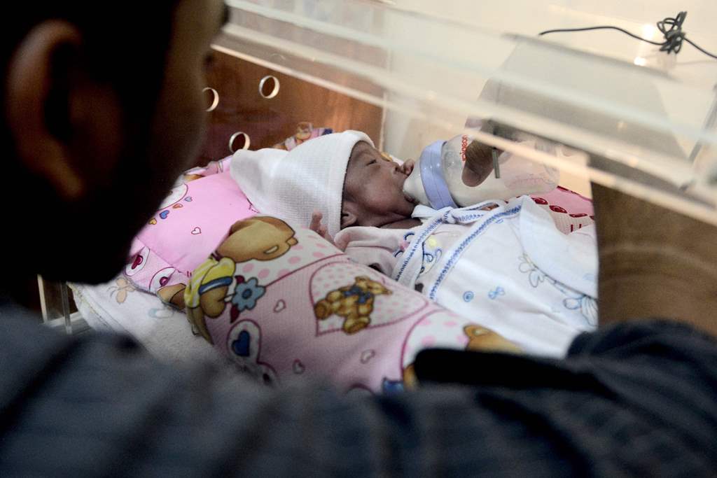 This photo taken on March 17, 2017 shows Prayogi feeding his daughter Maryamah Sudigyo, who was born prematurely, as she rests in an incubator in their home in Bogor. AFP / GOH Chai Hin 