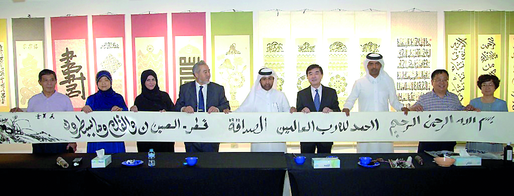 Katara General Manager Dr Khalid bin Ibrahim Al Sulaiti (centre) and Chinese Ambassador Li Chen (fourth right) with Chinese artists and other officials holding the nine-metre long poster adorned with various calligraphy techniques, texts and styles at the