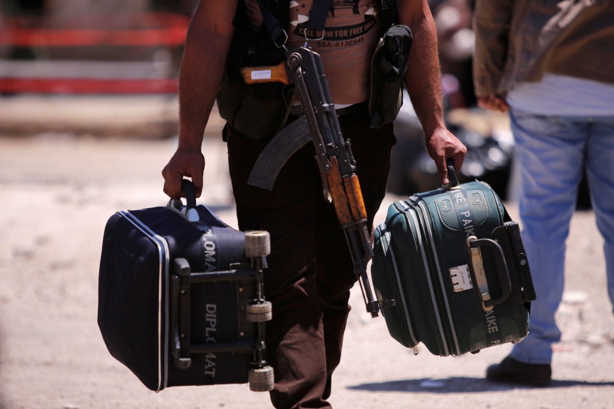 A rebel fighter carries suitcases and his weapon prior to boarding a bus as rebel fighters and their families evacuate the besieged Waer district in the central Syrian city of Homs, after an agreement reached between rebels and Syria's army, Syria May 21,