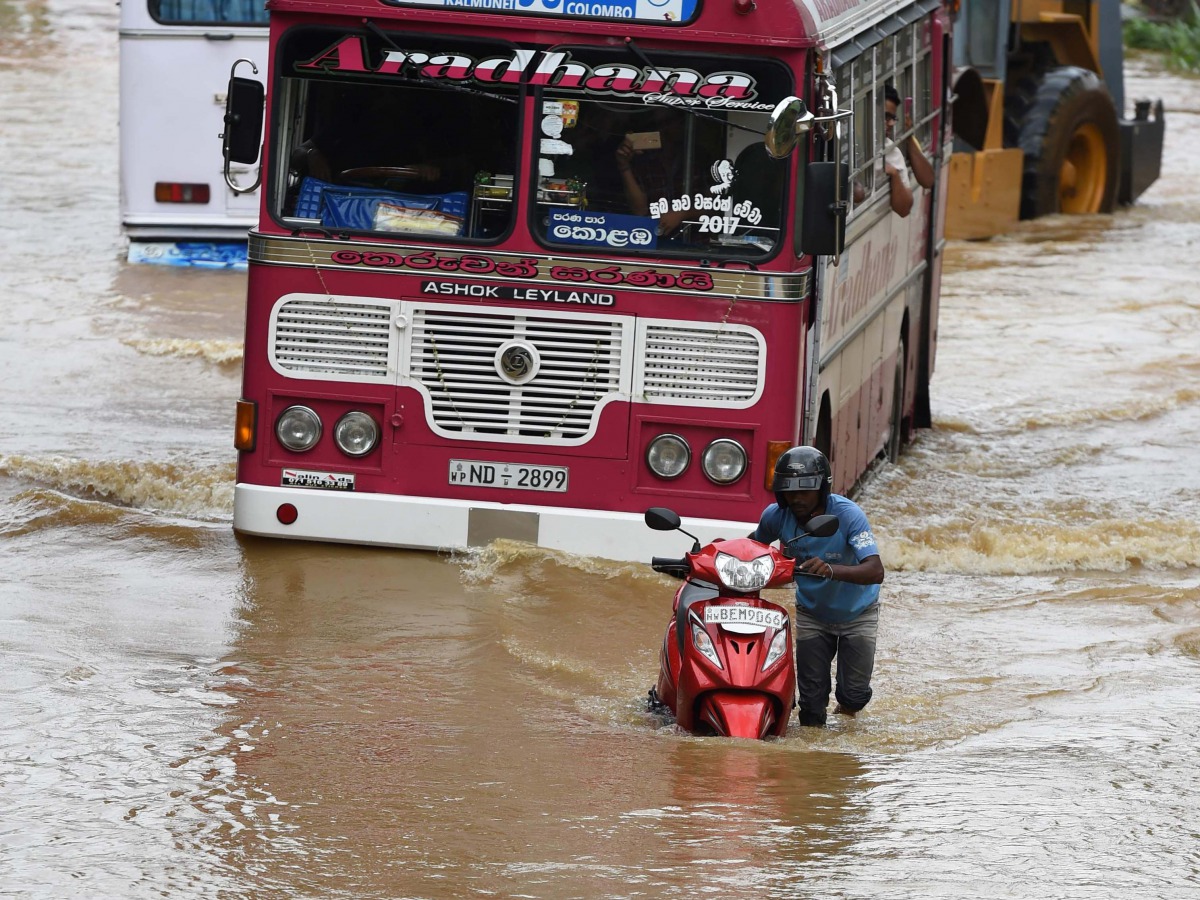 A Sri Lankan commuter pushes his motorbike through floodwaters on an expressway in the suburb of Athurugeriya in the capital Colombo on May 26, 2017. (AFP / Ishara S KODIKARA)