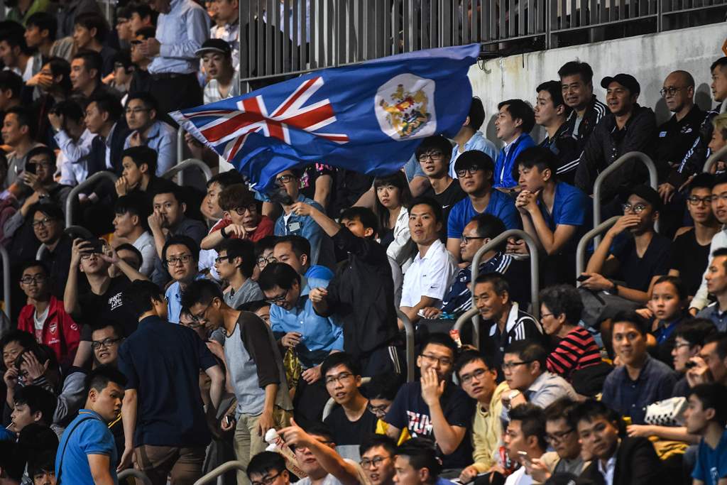 In this picture taken on April 25, 2017, a fan (C) of Hong Kong's Eastern waves the old British colonial flag of Hong Kong during the AFC Champions League football match between China's Guangzhou Evergrande and Hong Kong's Eastern at Mongkok Stadium in Ho